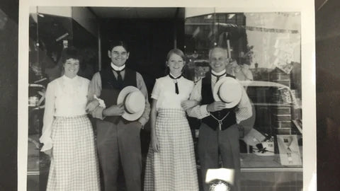Cyril Blowes and his team circa 1936, representing The Blowes Family Story with traditional attire and a storefront backdrop.