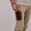 Jekyll and Hide - Compact Zip Around Cable Pouch - Tan | Black | Mocha held by a man in khaki pants.