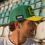 FIFA World Cup Australia Cap - Green. Man wearing a green and yellow cap with a logo in an outdoor setting.