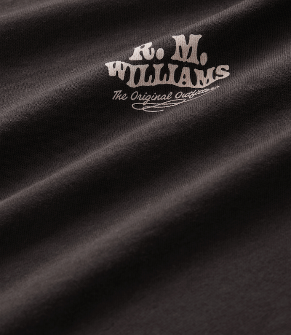 Close-up of a dark brown textured fabric with a light beige embroidered logo reading 'R.M.Williams