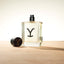 Ariat - Yellowstone - Eau de Cologne bottle prominently displayed with cap on wooden surface.