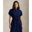 Woman wearing a blue Linen shirt dress, short sleeve, holding a straw bag - Polo Ralph Lauren - Belted Short-Sleeved Linen Shirt Dress - Newport Navy