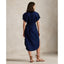 Woman wearing a blue Linen shirt dress, short sleeve, holding a straw bag - Polo Ralph Lauren - Belted Short-Sleeved Linen Shirt Dress - Newport Navy