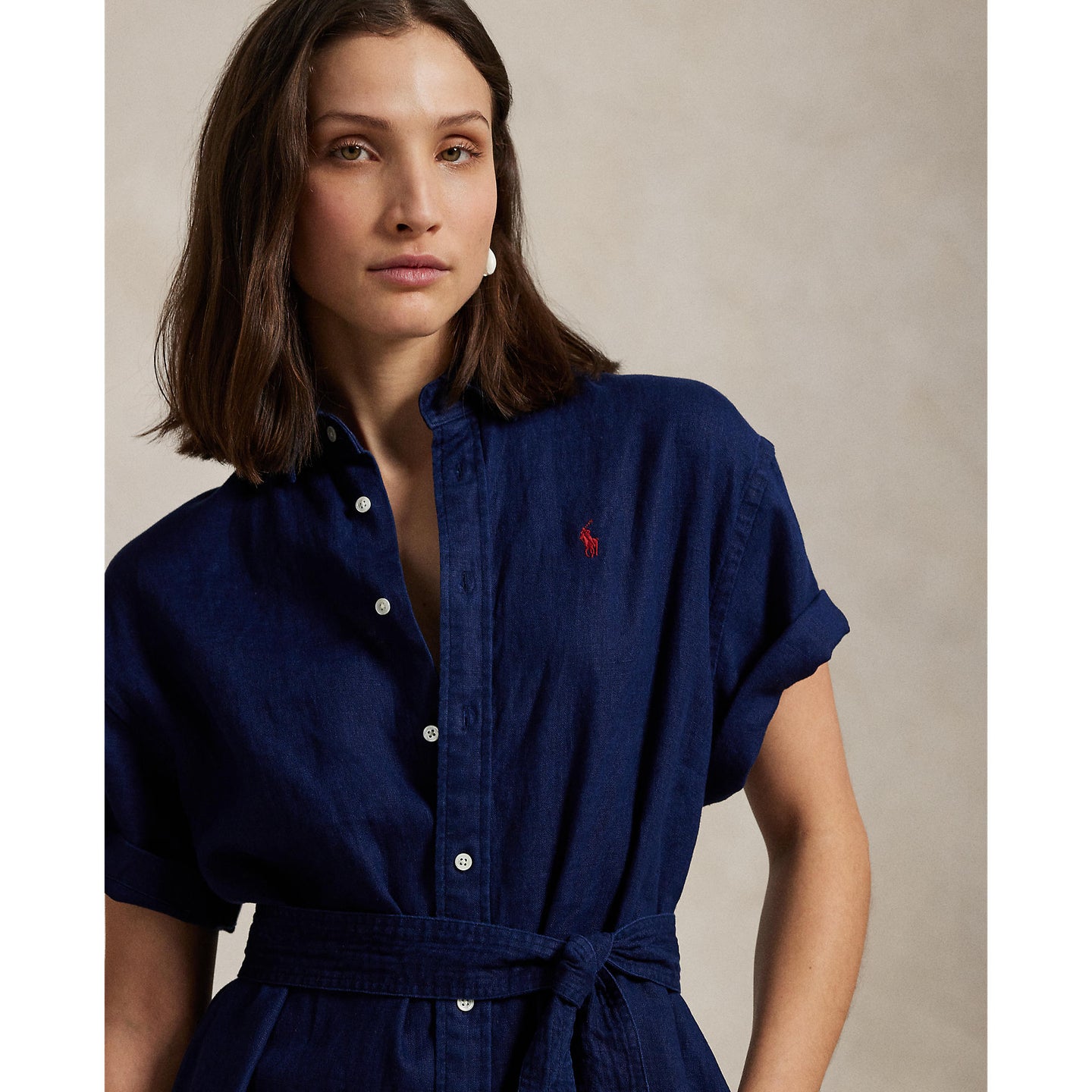 Woman wearing a blue Linen shirt dress, short sleeve, holding a straw bag - Polo Ralph Lauren - Belted Short-Sleeved Linen Shirt Dress - Newport Navy