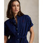 Woman wearing a blue Linen shirt dress, short sleeve, holding a straw bag - Polo Ralph Lauren - Belted Short-Sleeved Linen Shirt Dress - Newport Navy