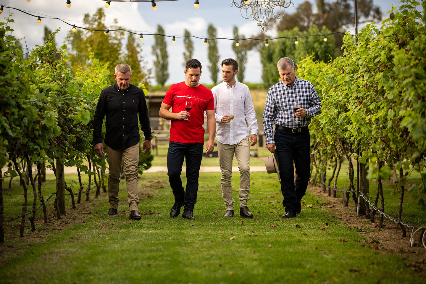 Four men walking through a vineyard, enjoying the outdoors and discussing The Fundamentals of Style.