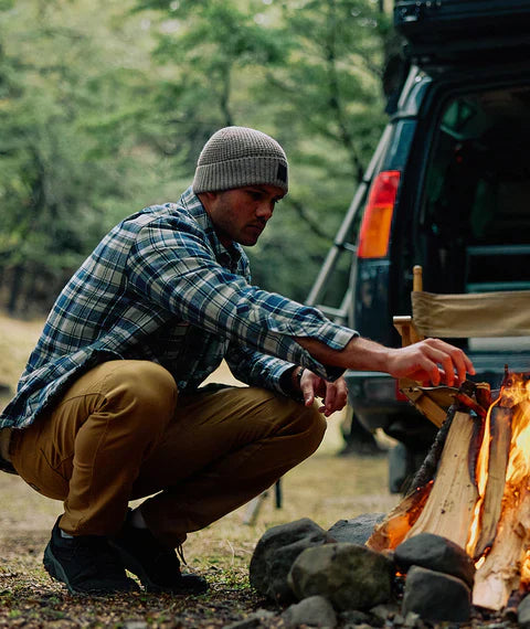 Winter Layering Tips That Link Across Shirts, Knits, Pants and Jackets - man layering clothes by campfire.