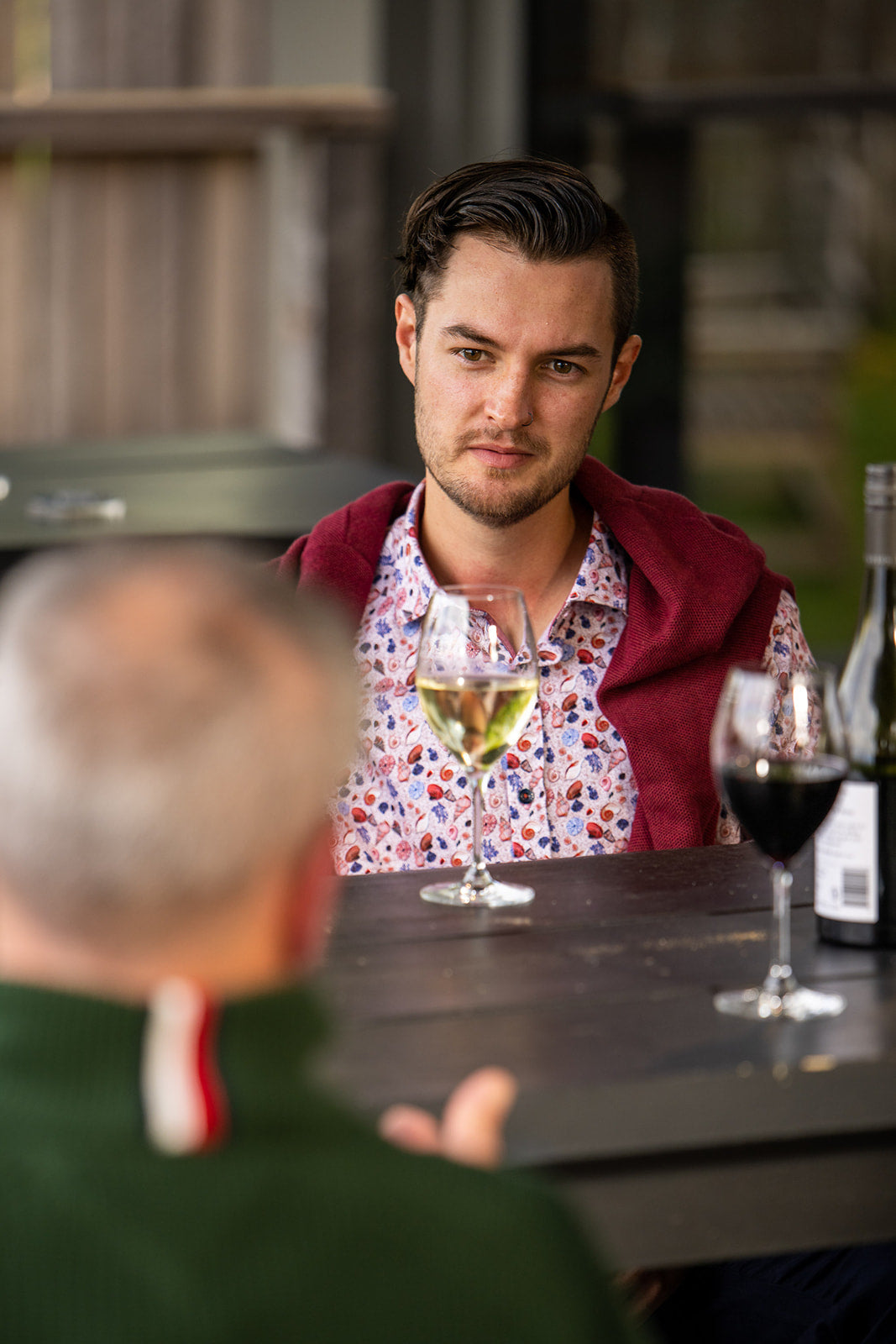 A man in a stylish smart casual outfit engaging in conversation over drinks, showcasing the nuances of smart casual dress.