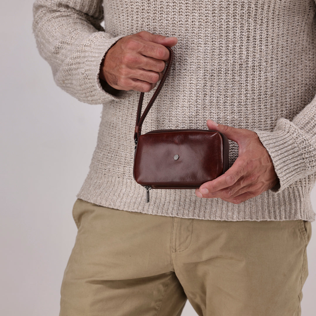 Jekyll and Hide - Compact Zip Around Cable Pouch - Tan | Black | Mocha held by a man in a cozy sweater.