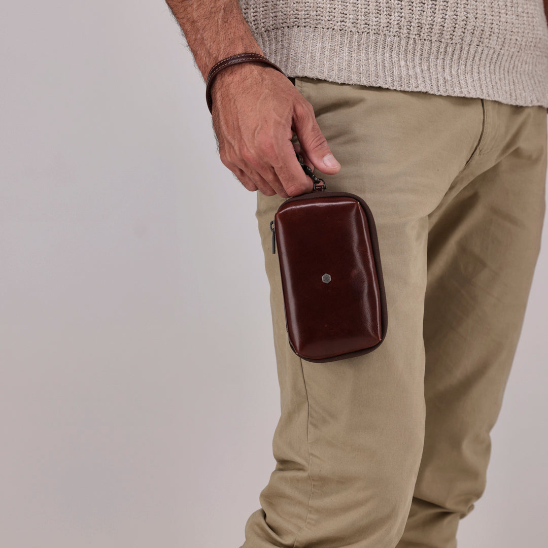 Jekyll and Hide - Compact Zip Around Cable Pouch - Tan | Black | Mocha held by a man in khaki pants.