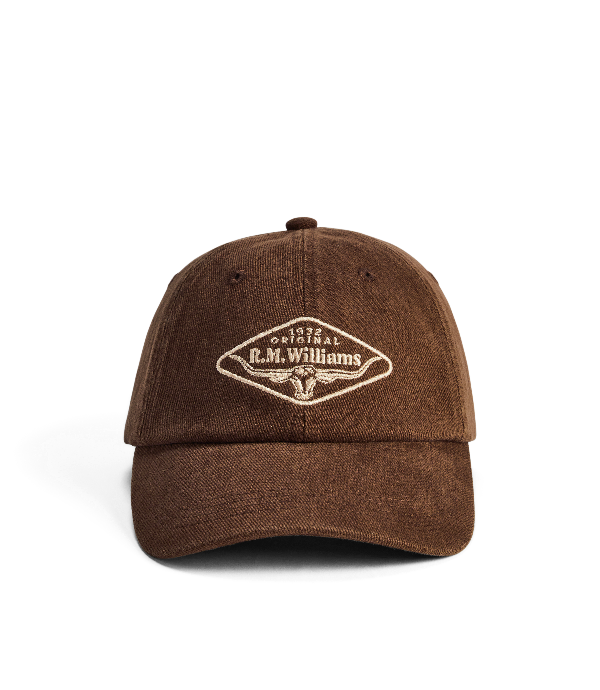 A brown cotton twill baseball cap with a curved brim, featuring a diamond-shaped embroidered patch on the front that reads 'R.M.