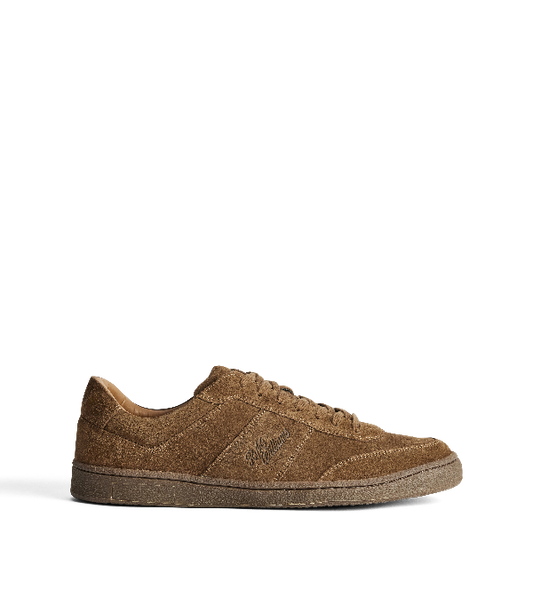 A single brown suede sneaker shown in profile against a clean white background. The shoe features tonal laces, a matching brown sole, and an embossed script logo on the side panel.