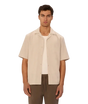 Man wearing a beige short-sleeve shirt over a white t-shirt on a white background
