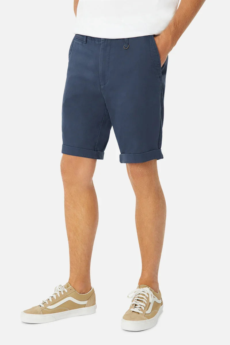 Person wearing navy shorts and beige sneakers on a white background