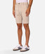 A person wearing light beige drawstring shorts, a pale pink top, and white sneakers with dark stripes, shown from the waist down against a light gray studio background.