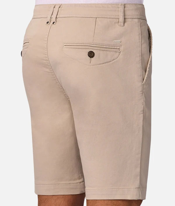 Close-up back view of a person wearing beige chino shorts with a buttoned welt pocket, waistband belt loops, and side pockets, against a light gray studio background.