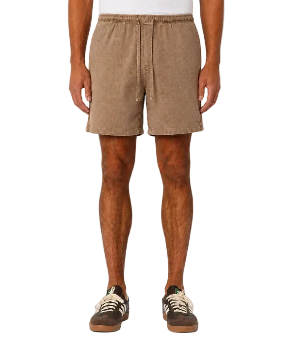 A person wearing tan corduroy drawstring shorts, shown from the waist down against a plain light gray studio background.