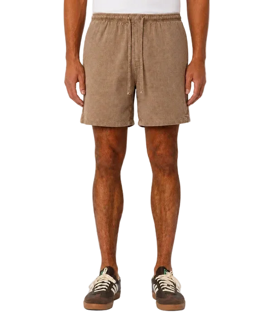 A person wearing tan corduroy drawstring shorts, shown from the waist down against a plain light gray studio background.