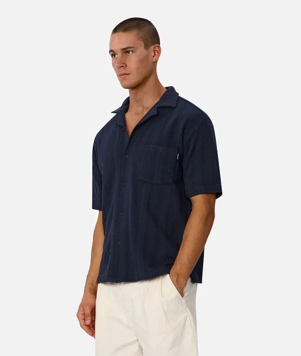 Man wearing a navy short-sleeve shirt with a white background
