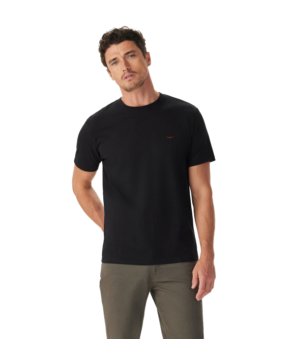 A man wearing a black short-sleeve crewneck t-shirt with a small red embroidered logo on the left chest, paired with olive green pants, photographed against a solid white background.