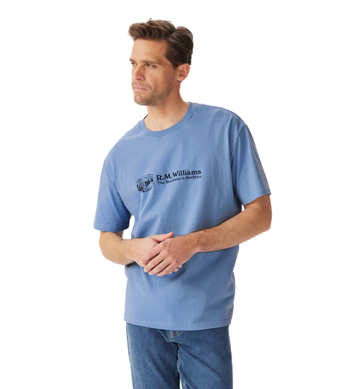 R.M.Williams - Outfitter T-Shirt - Soft Blue worn by a model, showcasing the crew neck and branded print.