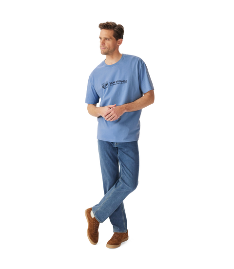 R.M.Williams - Outfitter T-Shirt - Soft Blue worn by a model, featuring crew neck and branded print.