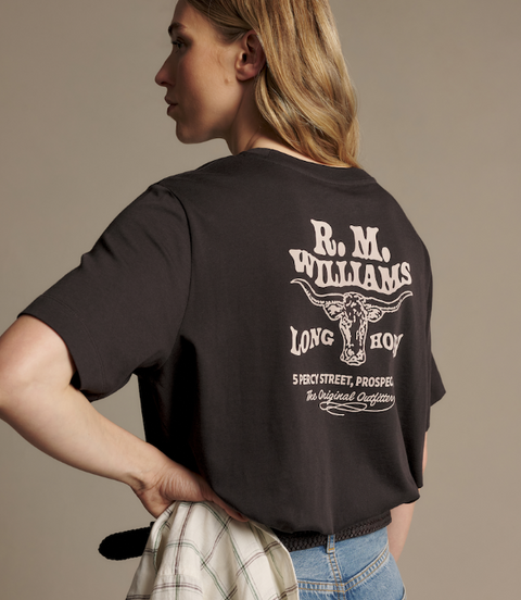 A woman shown from the back wearing a black graphic T-shirt with a large white 'R. M.