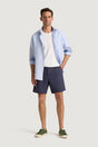 M.J. Bale - Menorca Side Tab Short- Denim model wearing a blue shirt and denim shorts with green sneakers.