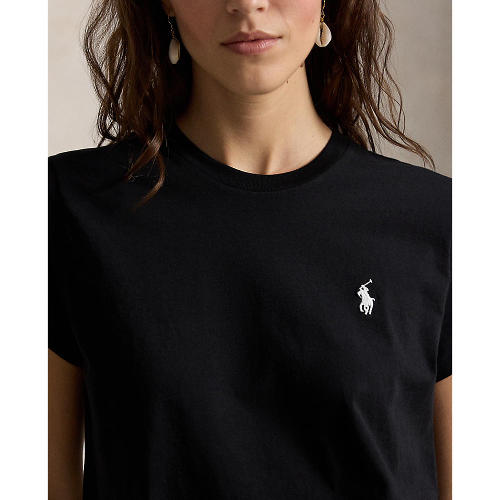 A close-up of a woman wearing a black short-sleeve crewneck t-shirt with the white embroidered Polo Ralph Lauren pony logo on the left chest.