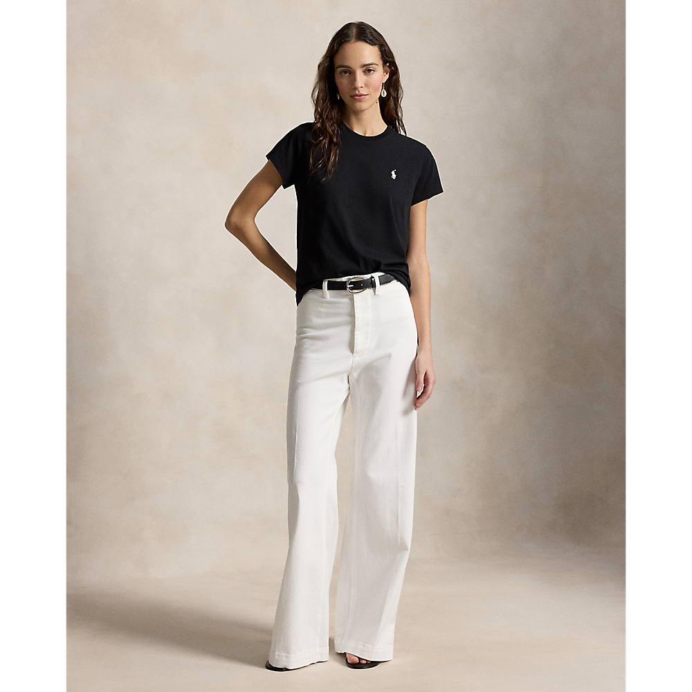 Woman wearing a black t-shirt and white pants against a beige background