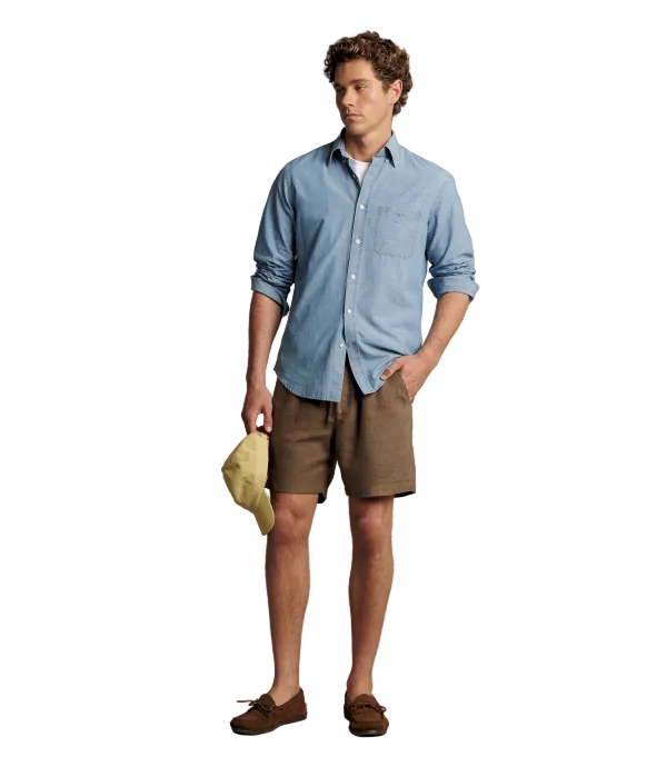 Man wearing brown linen shorts with a blue button up shirt. 