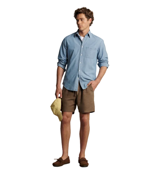 Man wearing brown linen shorts with a blue button up shirt. 