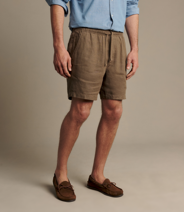 Man wearing brown linen shorts with a blue button up shirt. 