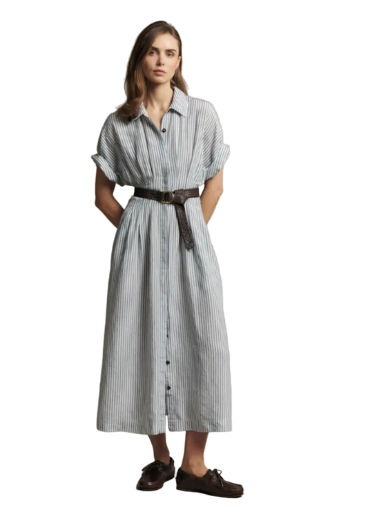 A woman modeling a light blue and white vertically striped midi shirt dress with a dark brown belt, paired with dark brown loafers, against a solid beige studio background.
