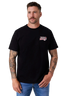A man wearing a black short-sleeve t-shirt with a small red, white, and blue graphic on the left chest, paired with blue jeans, against a light gray studio background.