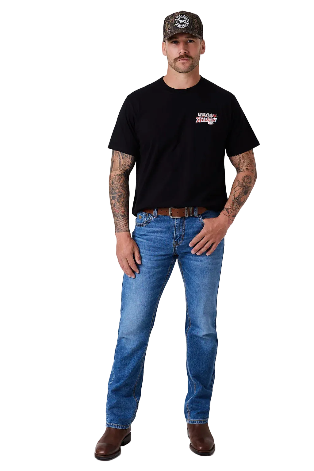A man modeling a black short-sleeve t-shirt with a small red and white graphic on the left chest, paired with blue jeans, a brown belt, and brown boots, standing against a light gray studio background.