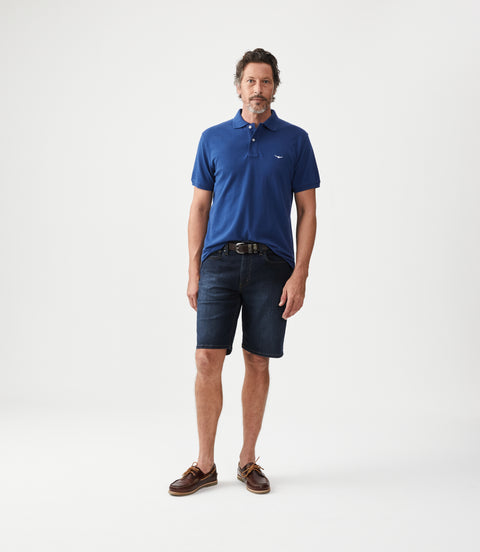 R.M.Williams - Nicholson Denim Short - Indigo showcased on a model wearing a blue polo and brown boat shoes.