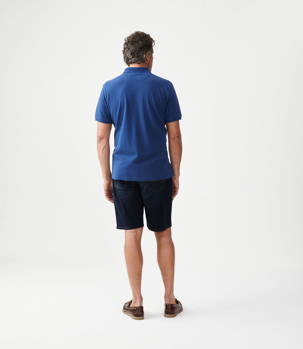 Man wearing R.M.Williams - Nicholson Denim Short - Indigo, viewed from the back, paired with a blue polo shirt.