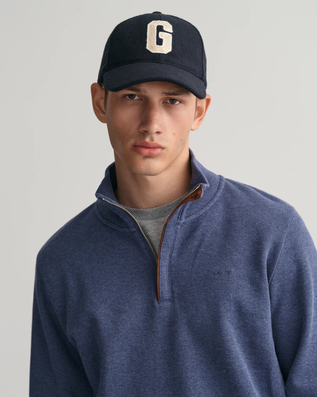 GANT - Sacker Rib Half-Zip Sweatshirt - Dark Jeans-Blue Melange modeled by a young man wearing a hat.