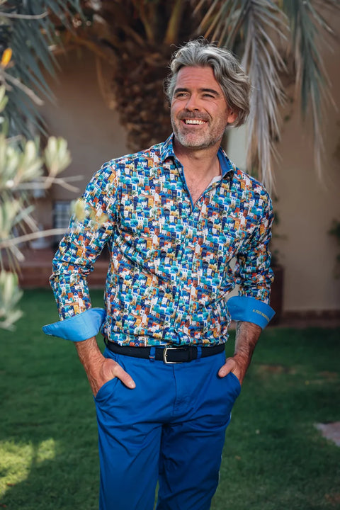 A Fish Named Fred - Shirt Town - Blue Multi worn by a smiling man in a green outdoor setting.