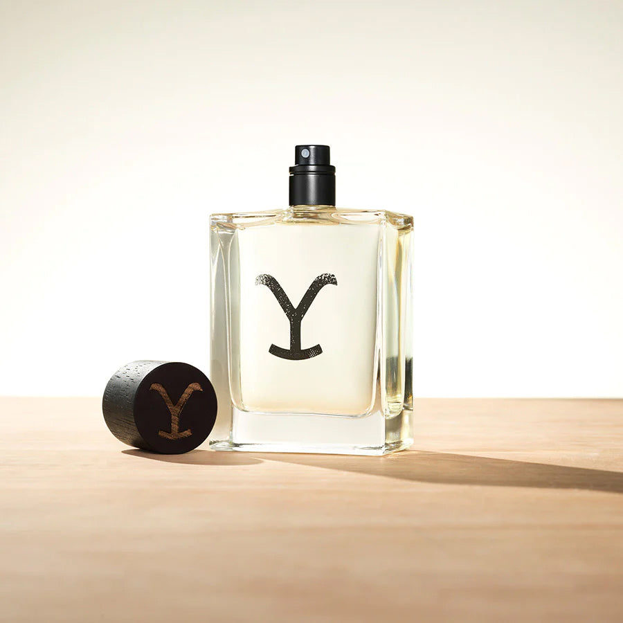 Ariat - Yellowstone - Eau de Cologne bottle prominently displayed with cap on wooden surface.