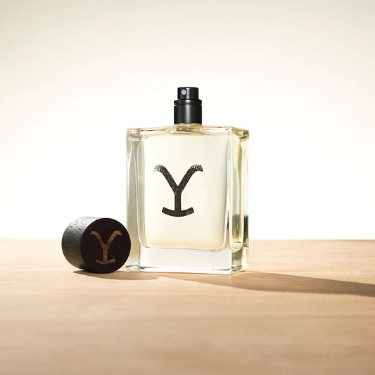 Ariat - Yellowstone - Eau de Cologne bottle prominently displayed with cap on wooden surface.