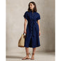 Woman wearing a blue Linen shirt dress, short sleeve, holding a straw bag - Polo Ralph Lauren - Belted Short-Sleeved Linen Shirt Dress - Newport Navy