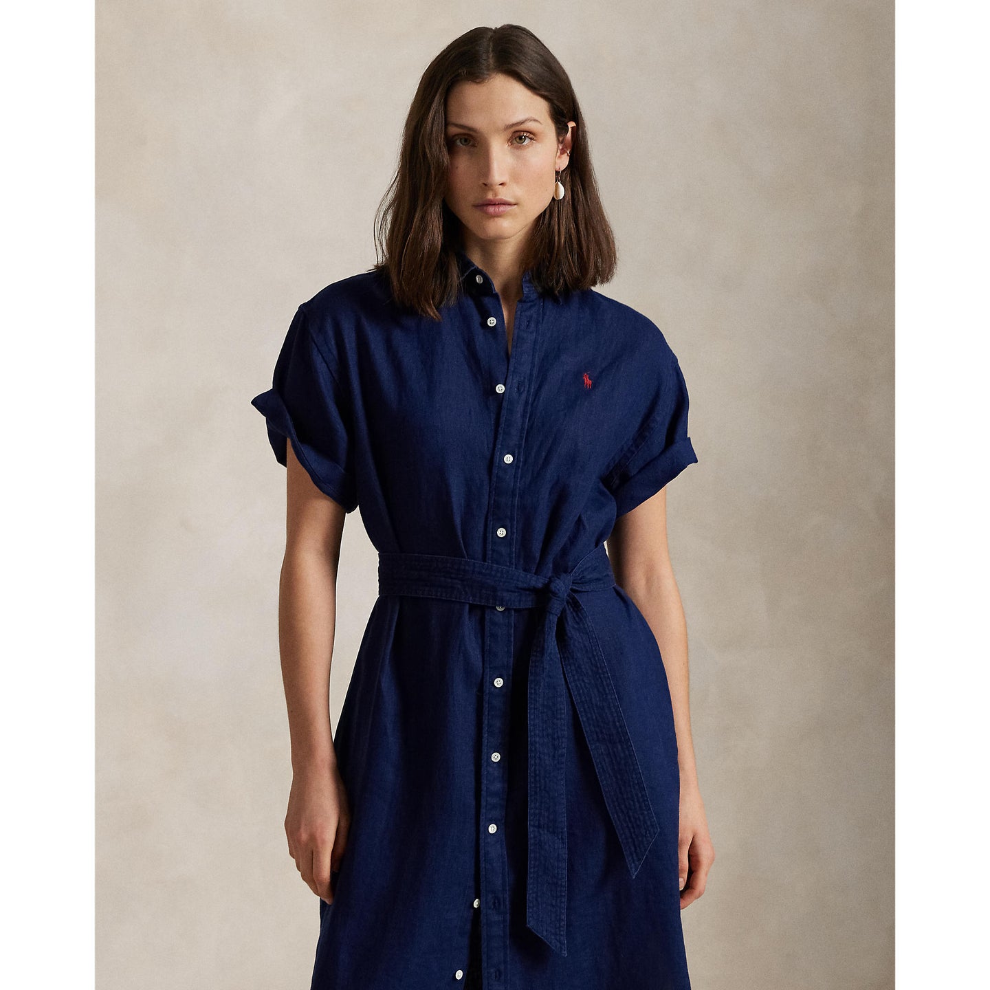 Woman wearing a blue Linen shirt dress, short sleeve, holding a straw bag - Polo Ralph Lauren - Belted Short-Sleeved Linen Shirt Dress - Newport Navy