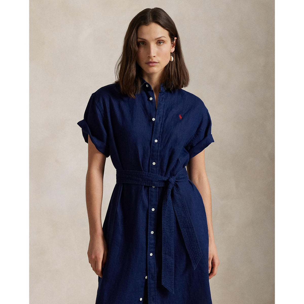Woman wearing a blue Linen shirt dress, short sleeve, holding a straw bag - Polo Ralph Lauren - Belted Short-Sleeved Linen Shirt Dress - Newport Navy