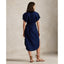 Woman wearing a blue Linen shirt dress, short sleeve, holding a straw bag - Polo Ralph Lauren - Belted Short-Sleeved Linen Shirt Dress - Newport Navy